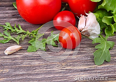 Fresh tomatoes with salad leaves on the table. Background. Stock Photo