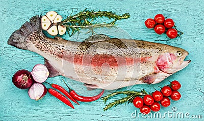 Fresh trout fish with vegetables on blue wooden table. Top view Stock Photo