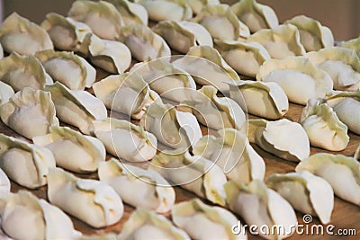 Freshly wrapped uncooked Chinese dumplings on cutting board Stock Photo