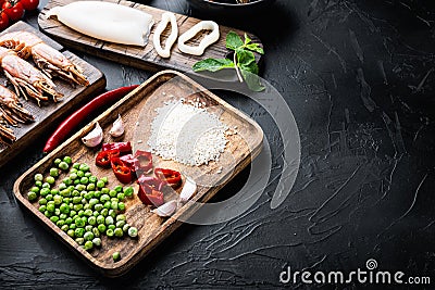 Fresh uncooked paella ingredients with king prawns, mussels and squid on black textured background with space for text Stock Photo