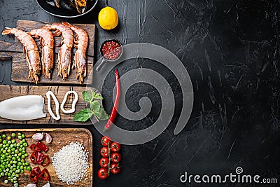 Fresh uncooked paella ingredients with king prawns, mussels and squid on black textured background, top view with space for text Stock Photo