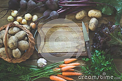 Fresh vegetables from carrot, beetroot, onion, garlic, potato on old board. Top view. Fall. Copy space on cutting board. Stock Photo