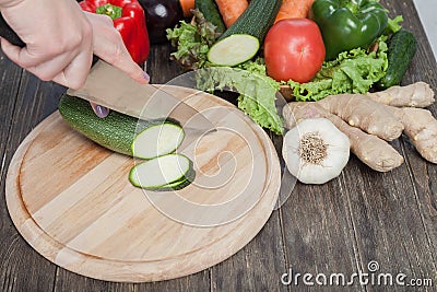 Fresh vegetables on chopping board and dark table. Zucchini cut into pieces, over a wooden table made a composition of vegetables Stock Photo