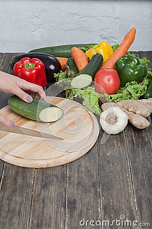 Fresh vegetables on chopping board and dark table. Zucchini cut into pieces, over a wooden table made a composition of vegetables Stock Photo