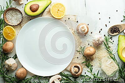 Fresh vegetables and mushrooms around a white plate for design, top view, space for copy. Healthy, clean food, vegan, detox, diet Stock Photo