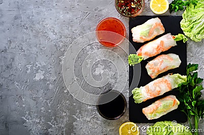 Fresh Vietnamese, Asian, Chinese food frame on grey concrete background. Spring rolls rice paper, lettuce, salad Stock Photo