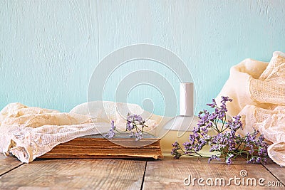 Fresh vintage perfume bottle next to aromatic flowers on wooden table. retro filtered image Stock Photo