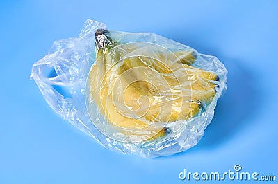 Fresh whole bunch of bananas in polietilene bag on purple background. Fruit purchasing concept Stock Photo