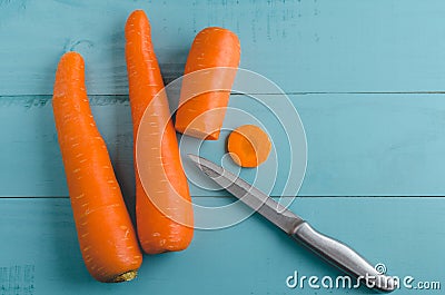 Fresh whole and sliced carrots with knife on blue wooden board Stock Photo