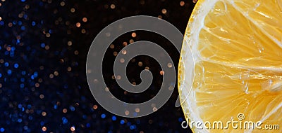 Fresh yellow lemon slice against shimmering dark background. Party cocktail ingredient. Bokeh from stars Stock Photo