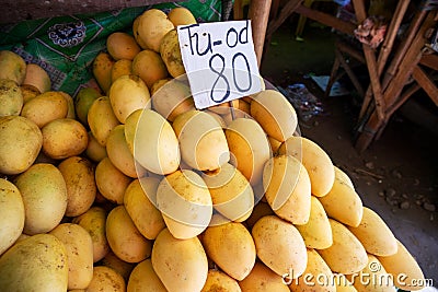 Fresh yellow mango pile with species name and price tag on rustic market stall. Asian fruit market stall. Philippine mango season Stock Photo