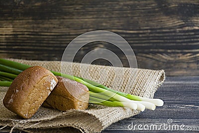 Freshly baked bread and green onion on a dark wooden background Stock Photo