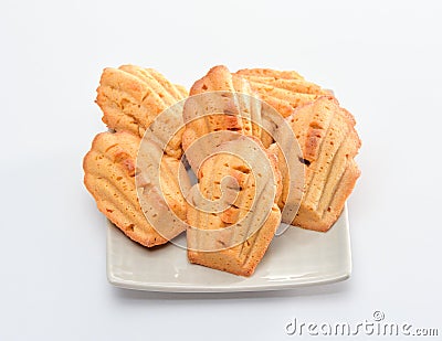 Freshly baked Madeleine cookies sprinkled with sugar powder close-up on the table, petite madeleine. Stock Photo