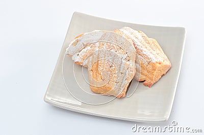Freshly baked Madeleine cookies sprinkled with sugar powder close-up on the table, petite madeleine. Stock Photo
