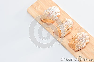 Freshly baked Madeleine cookies sprinkled with sugar powder close-up on the table, petite madeleine. Stock Photo