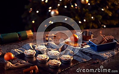 Freshly Baked Mince Pies On Table Set For Christmas With Tree Lights In Background Stock Photo