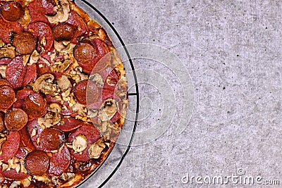 Freshly baked pizza with salami and sujuk sausage slizes, mushrooms and mozzarella cheese on grid with empty copy space Stock Photo