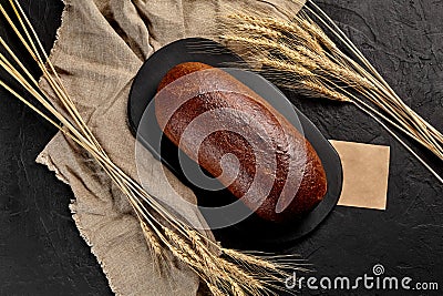 Whole rye bread with ears of wheat, burlap and piece of craft paper Stock Photo