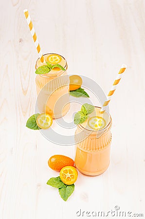 Freshly blended orange citrus kumquat fruit smoothie in glass jars with straw, mint leaf, cute ripe berry, copy space. Stock Photo