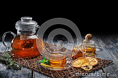 Freshly brewed black tea with mint and cookies, honey and glass teapot on a wooden table Stock Photo