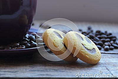 Freshly brewed coffee in a violet cup with cookies on the background of coffee beans Stock Photo