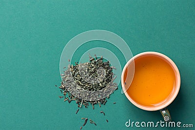 Freshly Brewed Green Tea in Ceramic Cup. Loose Leaves Scattered on Solid Dark Background. Chinese Japanese Asian Cuisine. Healthy Stock Photo