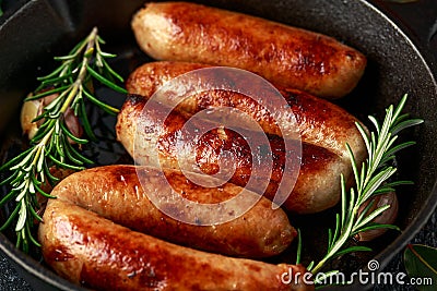 Freshly cooked butchers made, homemade sausages with rosemary in cast iron frying pan Stock Photo