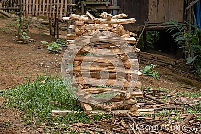 Freshly cut stacked firewood in front of a wooden house. Chopped firewood used for cooking in an outdoor kitchen. Stock Photo