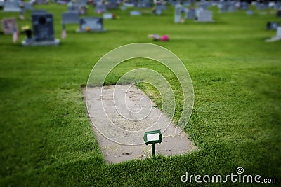 Freshly Dug Grave in Cemetery with Headstones and Green Grass Stock Photo