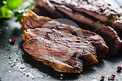 Freshly grilled beef steak on slate plate with salt pepper rosemary and parsley herbs. Sliced pieces of juicy beef steak Stock Photo