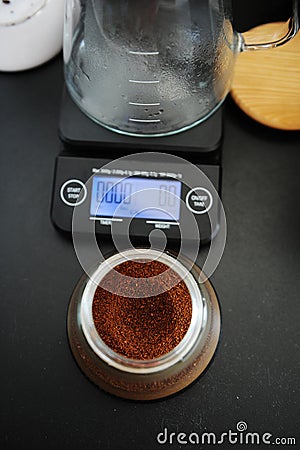 Freshly ground coffee in a manual coffee grinder container top view. Electronic scales with timer Stock Photo