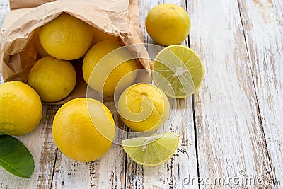 Freshly lemons in paper bag on white wooden table Stock Photo