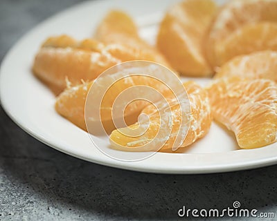 Freshly peeled and ready to eat sections of a giant tangerine on a white plate Stock Photo