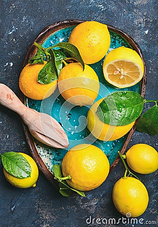 Freshly picked lemons with leaves in bright blue ceramic plate Stock Photo