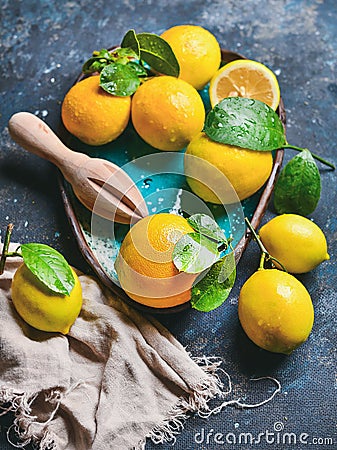 Freshly picked lemons with wet leaves in blue ceramic plate Stock Photo