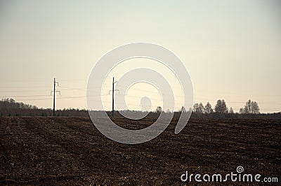 Freshly plowed field and power line with pillars passing through it. Landscape Stock Photo