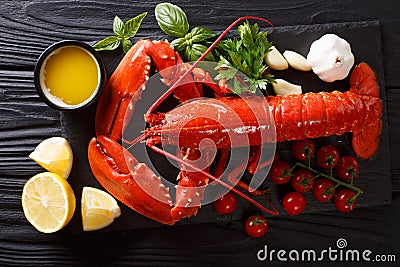 Freshly prepared lobster closeup with lemon, garlic, fresh tomatoes and herbs on a table. Horizontal top view Stock Photo