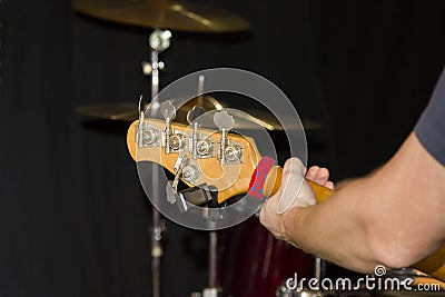 Fretboard of a five string bass guitar with a musician`s hand on the background of a drum kit in the Studio Stock Photo