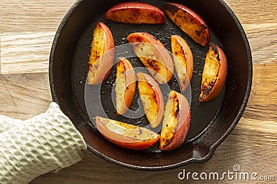 Fried apple, Pink Lady variety, in a cast iron frying pan. On a chopping board in a kitchen Stock Photo