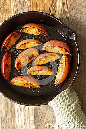 Fried apple, Pink Lady variety, in a cast iron frying pan. On a chopping board in a kitchen Stock Photo