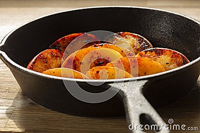 Fried apple, Pink Lady variety, in a cast iron frying pan. On a chopping board in a kitchen Stock Photo