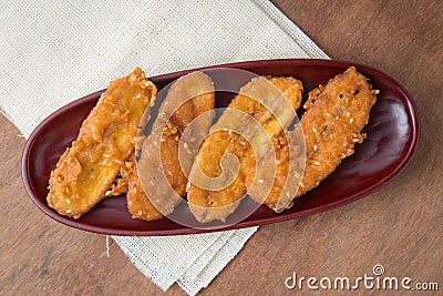 Fried bananas in wooden plate on white linen, Kluay Tod - Thai dessert Stock Photo