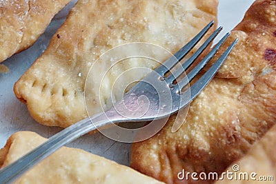 Fried chebureks on the table close-up fork lies on top Stock Photo