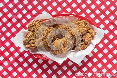 Fried chicken basket on red checkerboard tablecloth in center Stock Photo