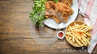 Fried chicken crispy and salad lettuce on white plate with french fries basket ketchup on wooden dining table Stock Photo