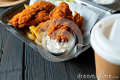 Fried chicken and french fries and in a takeaway container on the wooden background. Food delivery and fast food concept Stock Photo