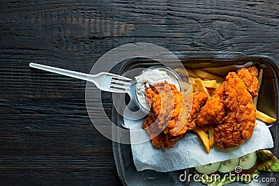 Fried chicken and french fries and in a takeaway container on the wooden background. Food delivery and fast food concept Stock Photo