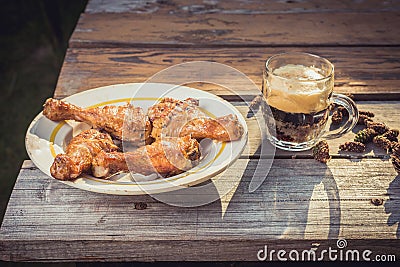 Fried chicken legs with beer on a wooden table/Fried chicken legs with beer on a picnic on a sunny day Stock Photo