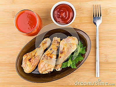 Fried chicken legs in black dish, tomato juice and sauce Stock Photo