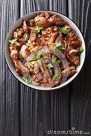 Fried chicken offal liver, heart and stomachs with onions, tomatoes and spices close-up in a bowl. vertical top view Stock Photo